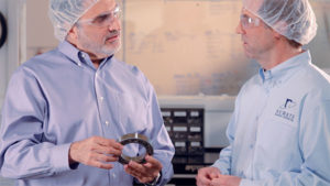 Schatz Bearing workers talking while holding a ball bearing